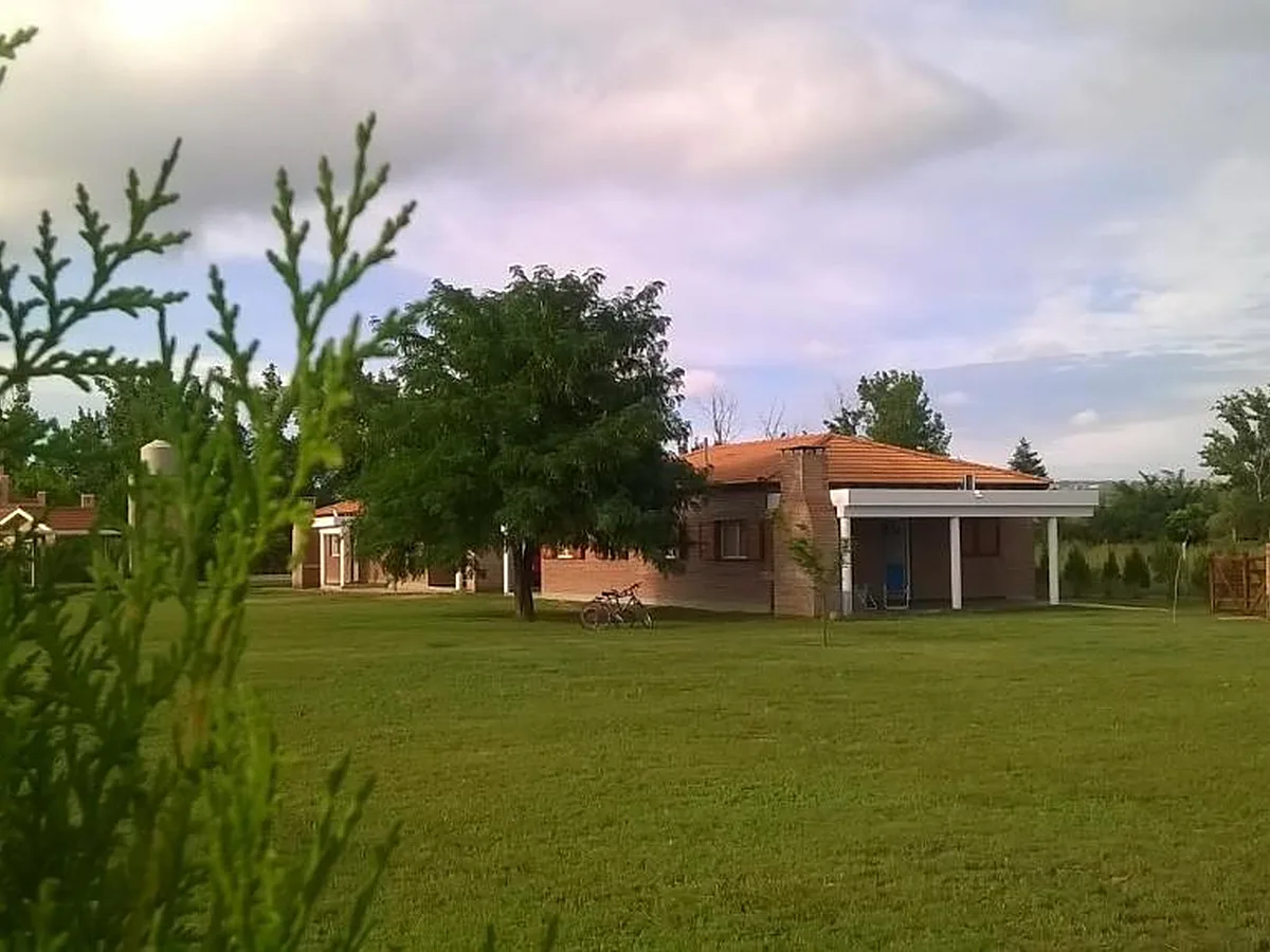 Parque de césped con una cabaña de ladrillo y árboles