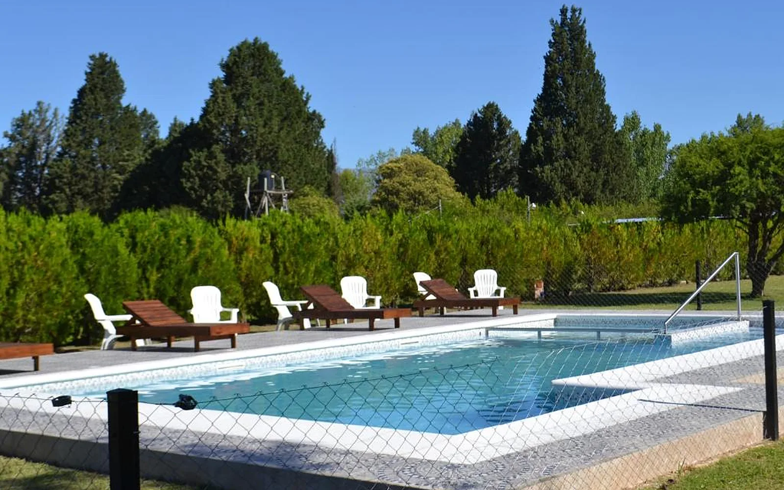 Pileta con reposeras, el parque y las cabañas de Aguas Mornas