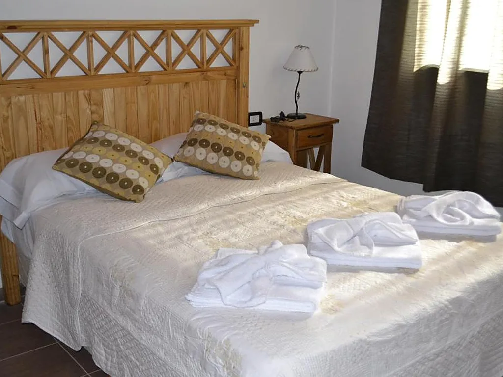 Dormitorio con respaldo de madera tallada, Aguas Mornas, cabañas en Mina Clavero